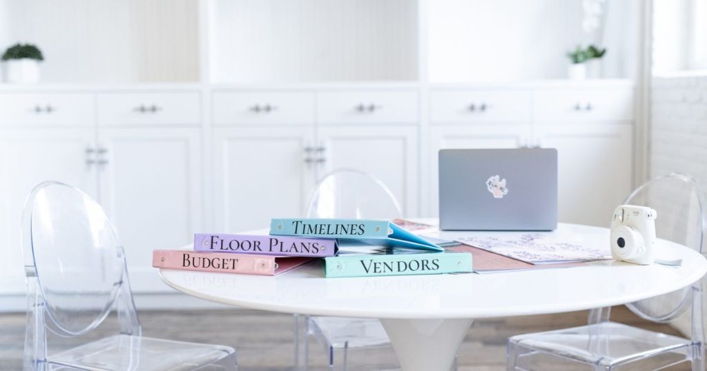 A desk with wedding planning binders for wedding vendors, timelines, floor plans, and budgets. This photo shows planning for any wedding day emergencies with a wedding emergency kit.