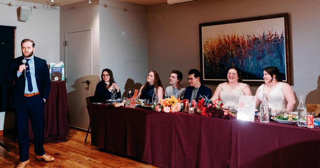 Brides sit at head table at reception of DC Pinstripes wedding.