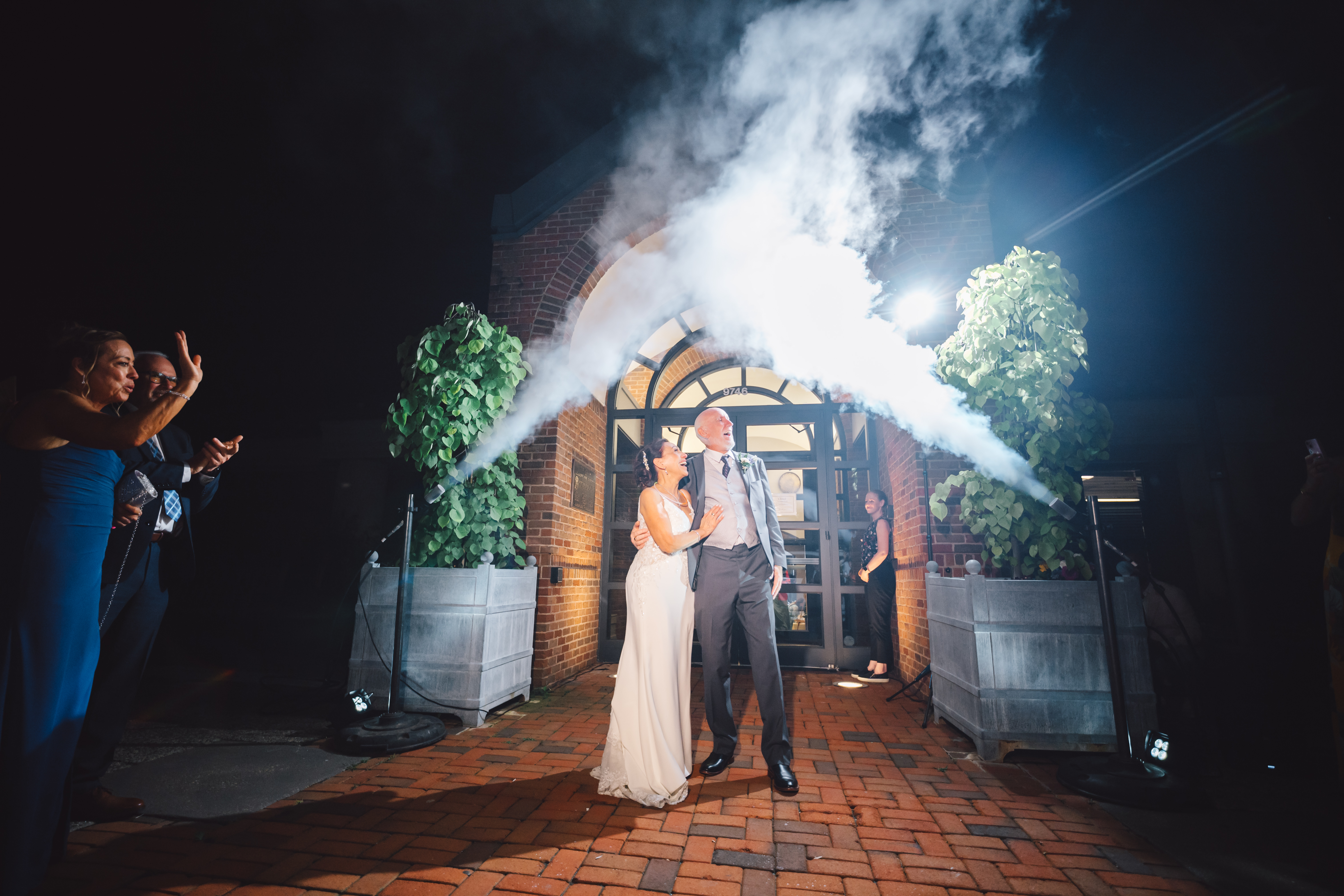 couple exiting in front of doors with air cannons going off in back