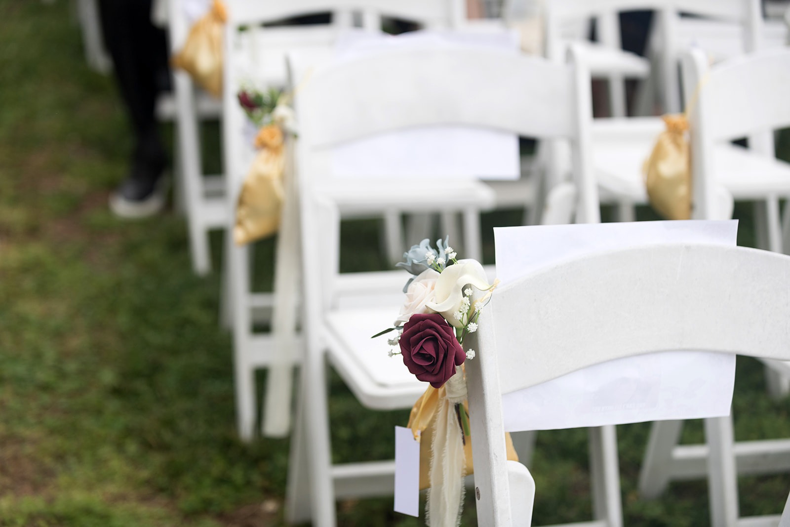 close up of white ceremony chairs with rose detailing