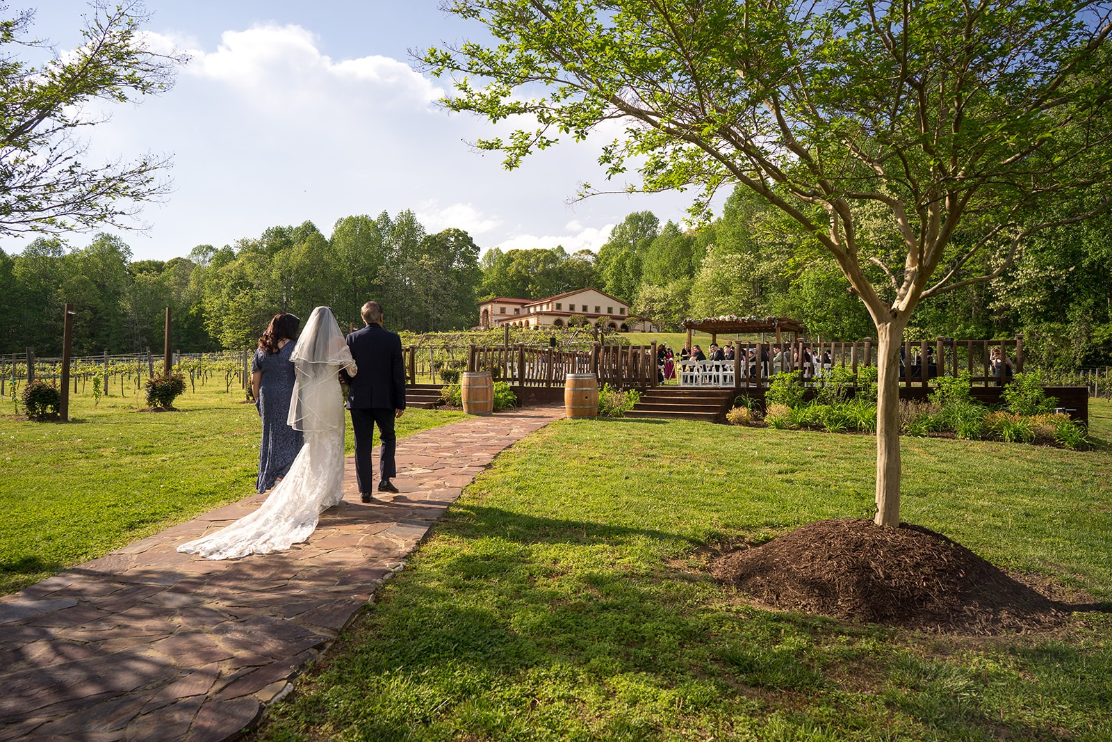 bride and parents on each arm walking into the ceremony