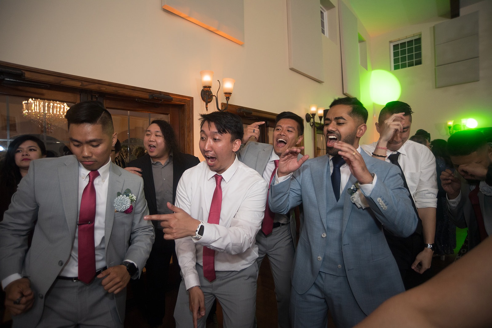 groomsmen pointing and dancing in ballroom reception