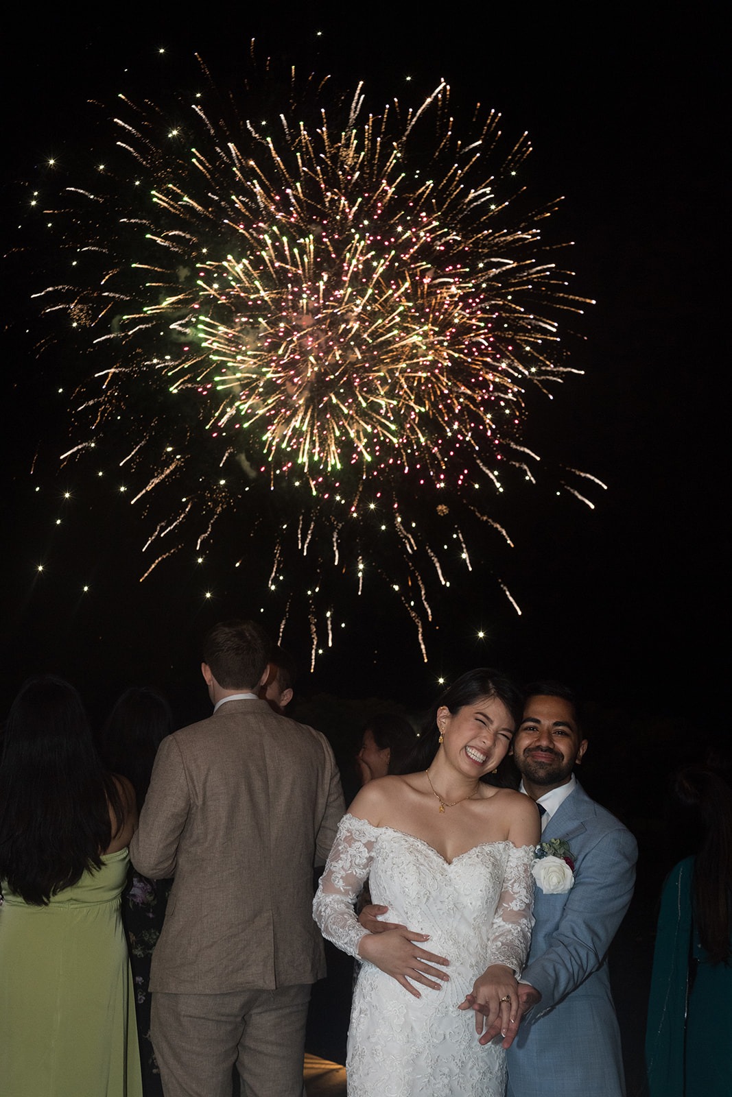 grooms hugging bride with golden fireworks going off in the background