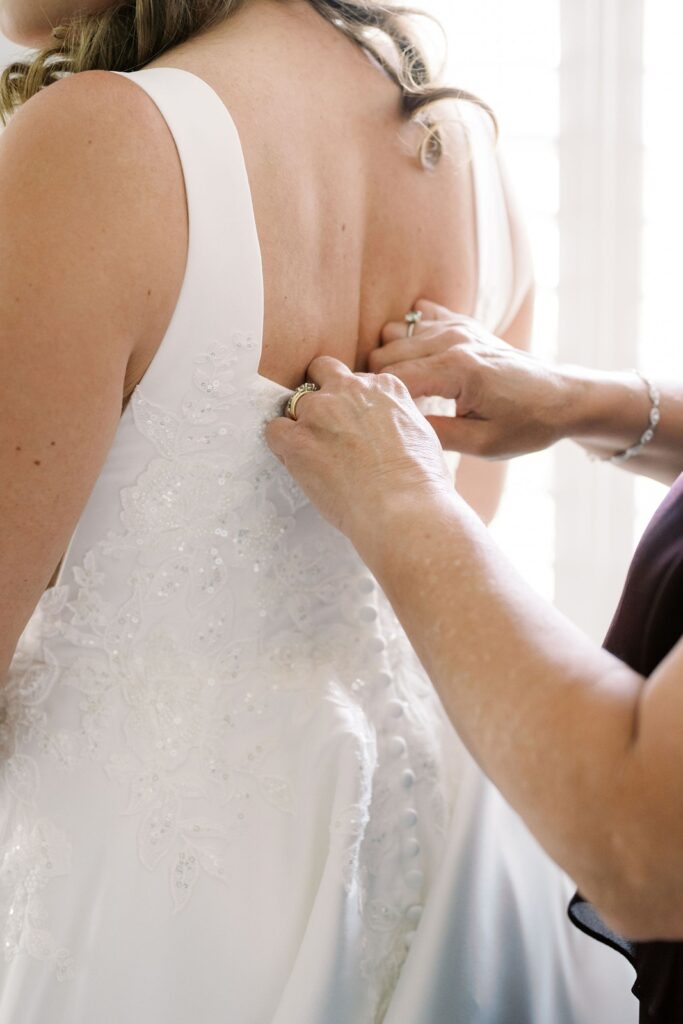 A women helping a bride alter the back of her wedding dress.