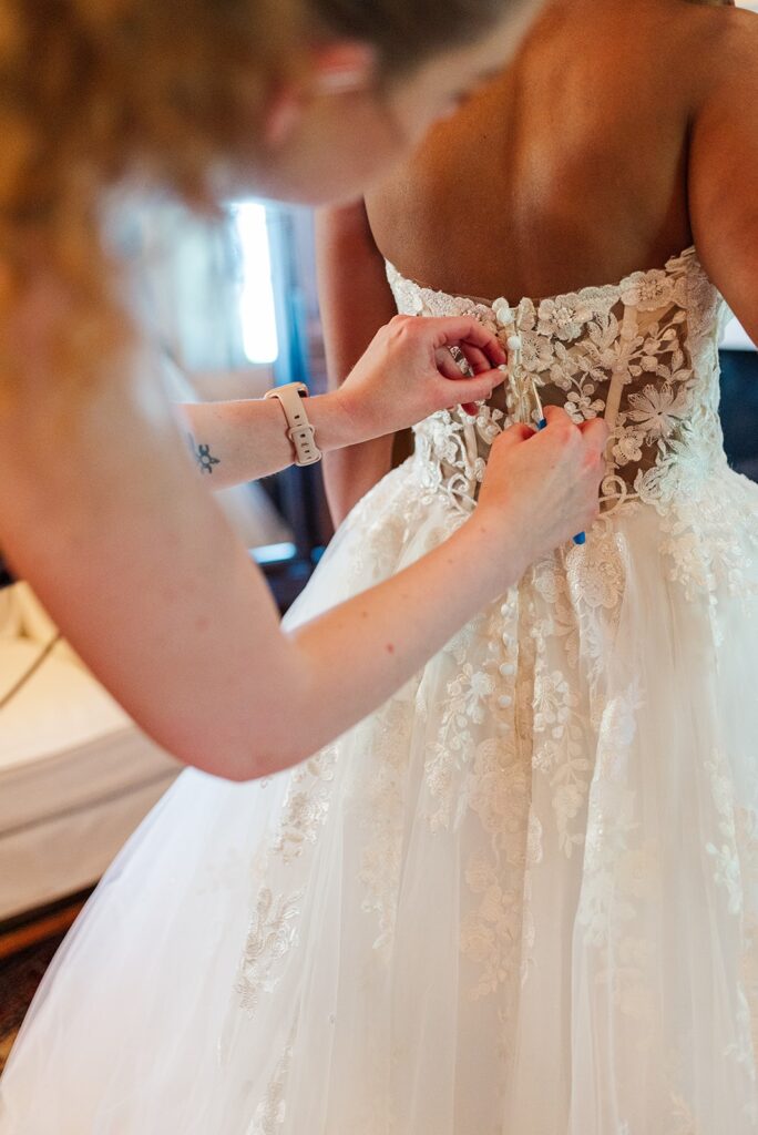 Kinfete Weddings & Events founder, Kristy helping a bride adjust the back of her wedding dress.