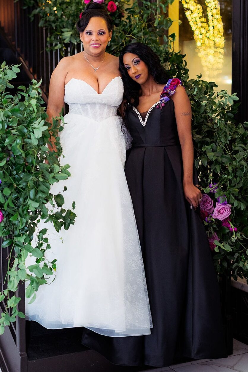 Two brides posing on a floral staircase at their Citizens Ballroom Wedding.