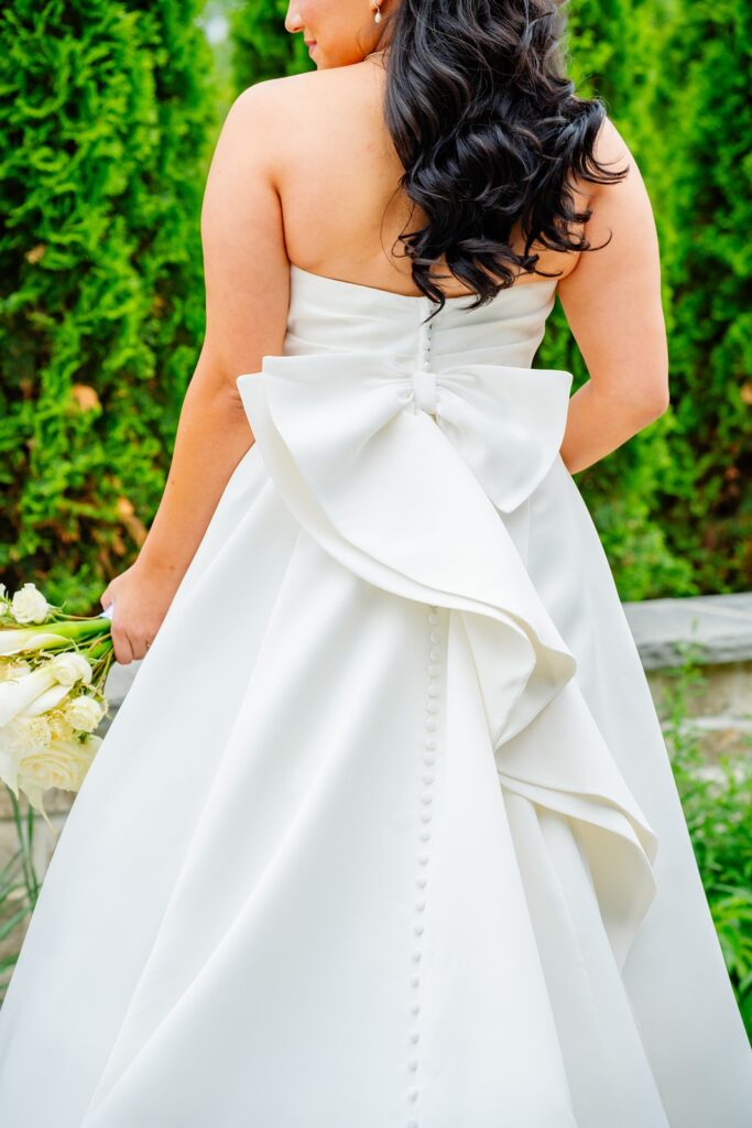 Woman posing in a wedding dress with a bow detail on the back.