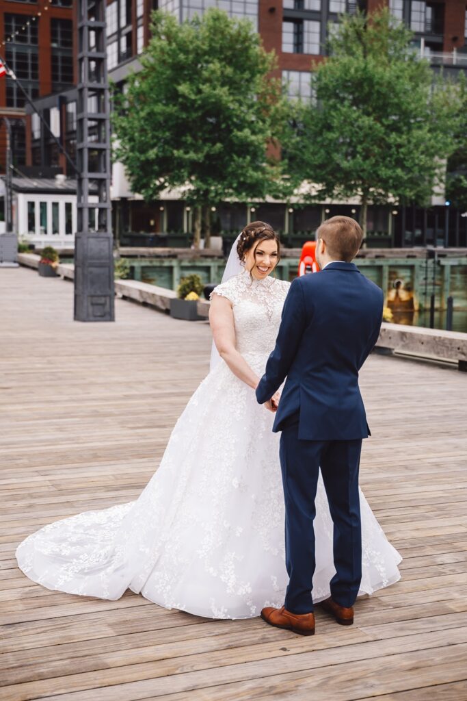 A couple stands in front of the Intercontinental DC Wharf Hotel looking at each other for wedding portraits.