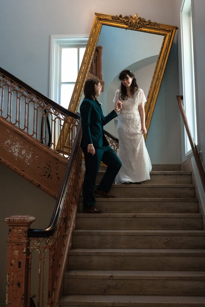 Weeding couple looks at each other as they walk down a stair case with a large mirror behind them at The Line DC Hotel.