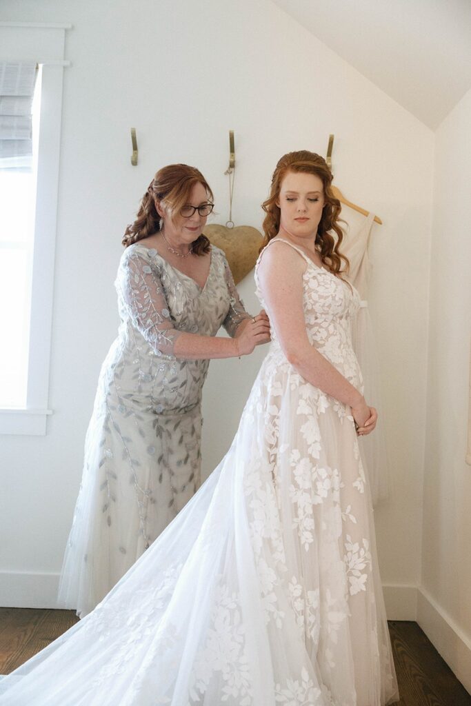 A spouse-to-be with her mother fixing her wedding dress in the Showalter's Orchard and Greenhouse farmhouse