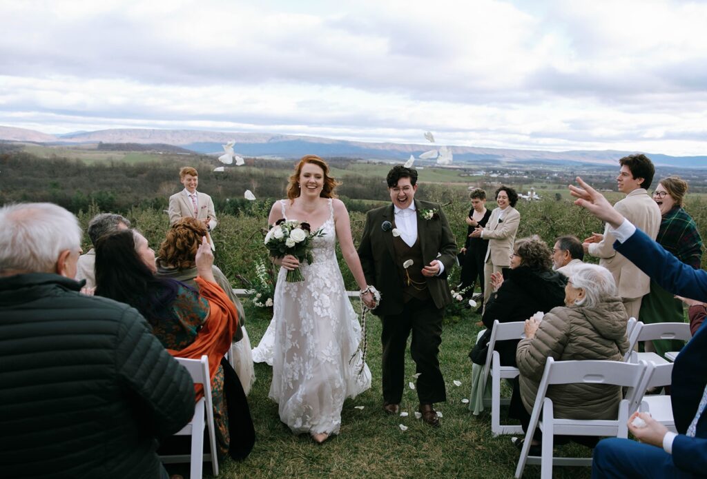A couple walking down the aisle while being showered with rose petals