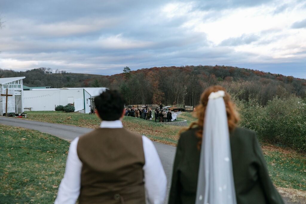 A couple overlooks a hill in the Shenandoah Valley watching their guests at cocktail hour