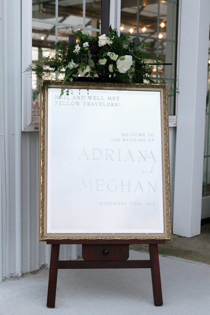 An etched welcome mirror outside of a wedding reception
