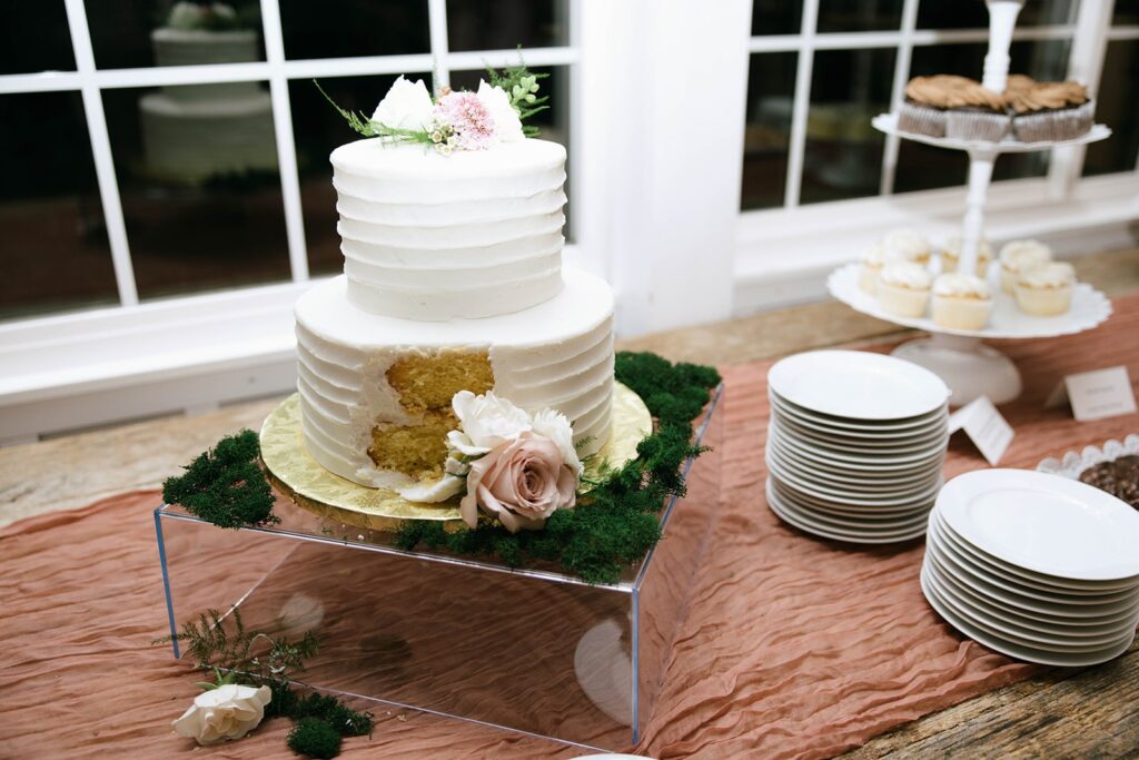 A cut wedding cake on a terracotta colored table scape